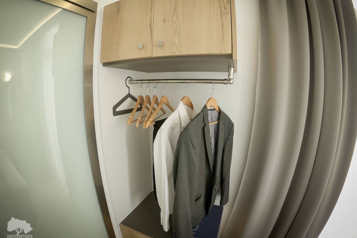 Un baño moderno con un mueble de madera sobre un espejo, un perchero con ganchos y una cortina de ducha.