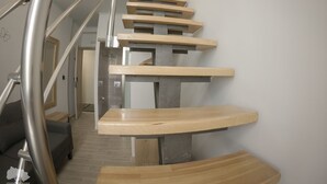 A spiral staircase with wooden steps and metal railings, leading to an upper floor.