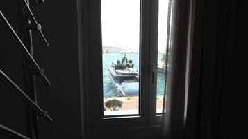Vista a través de una puerta con ventana, que muestra un barco y una costa lejana.