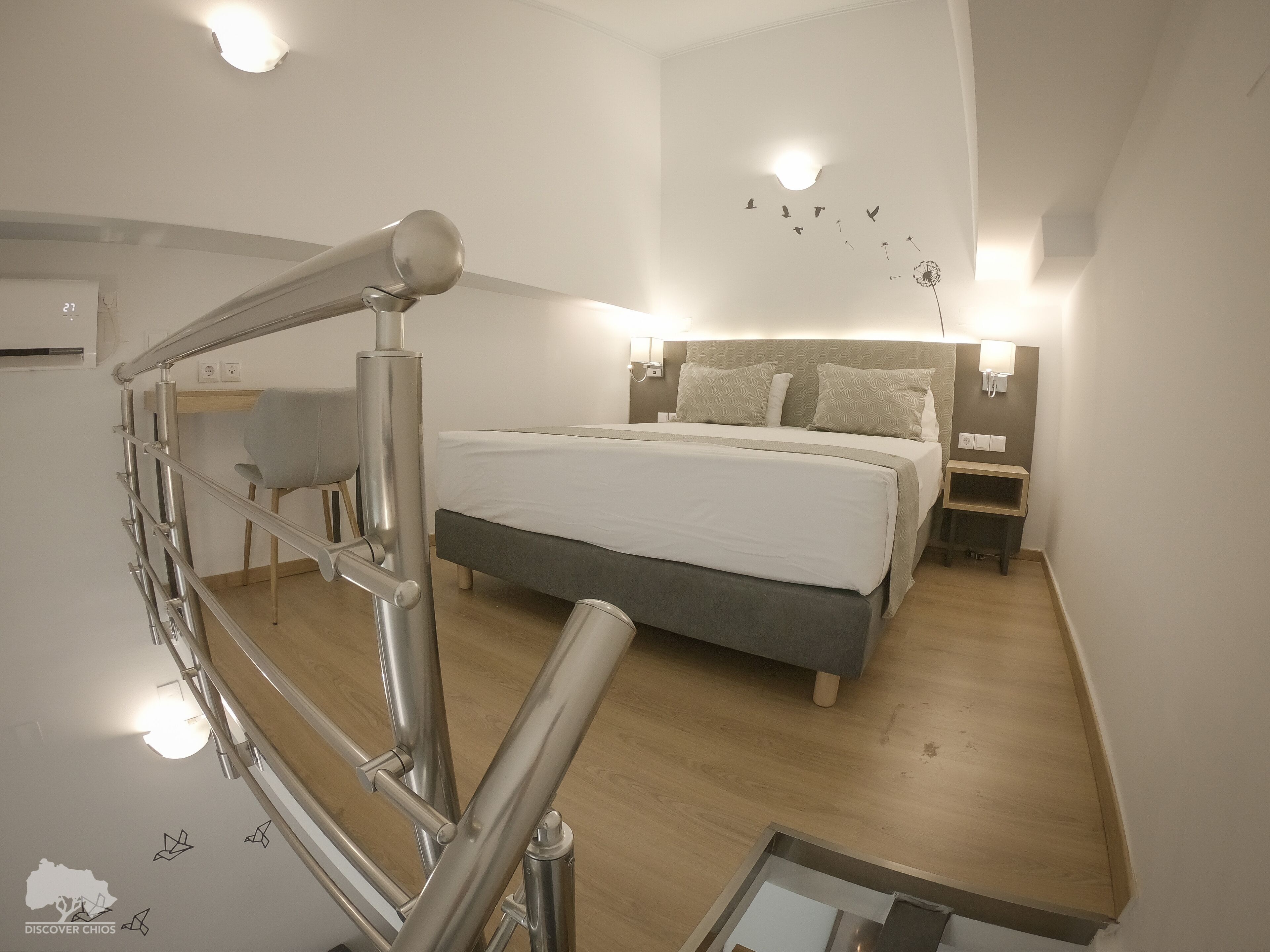 Ein modernes Hotelzimmer mit einem großen Bett, einem Schreibtisch und einer Wendeltreppe.