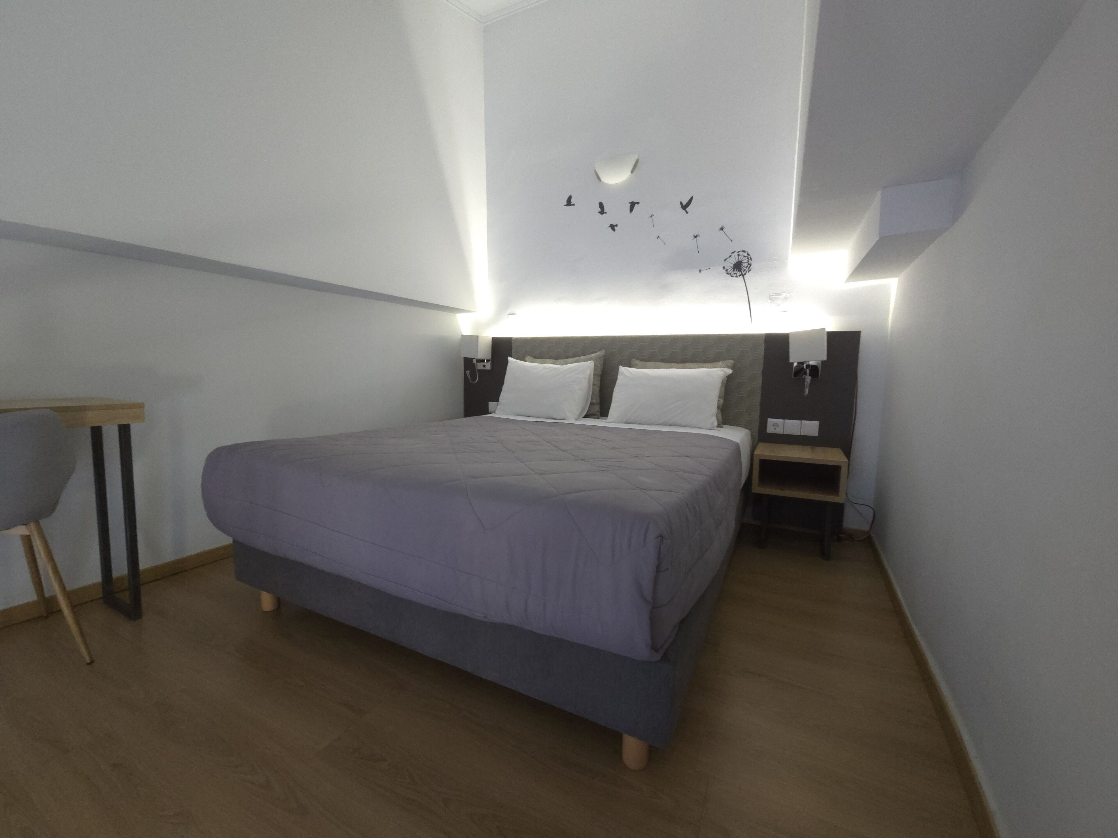 A modern bedroom with a large bed, bedside tables, and a wall-mounted light fixture.
