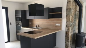 Eine moderne Küche mit einer zentralen Kochinsel, integrierten Geräten und einer Wand mit Steinverkleidung.