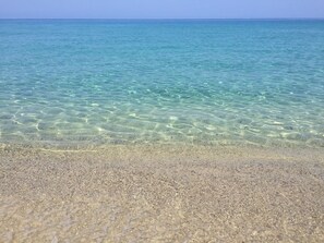 En tydlig vy över en strand med grunt vatten och en sandstrand.