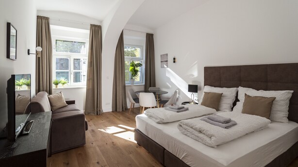 Ein modernes Schlafzimmer mit einem großen Bett, einer Couch, einem Schreibtisch und einem Sessel.