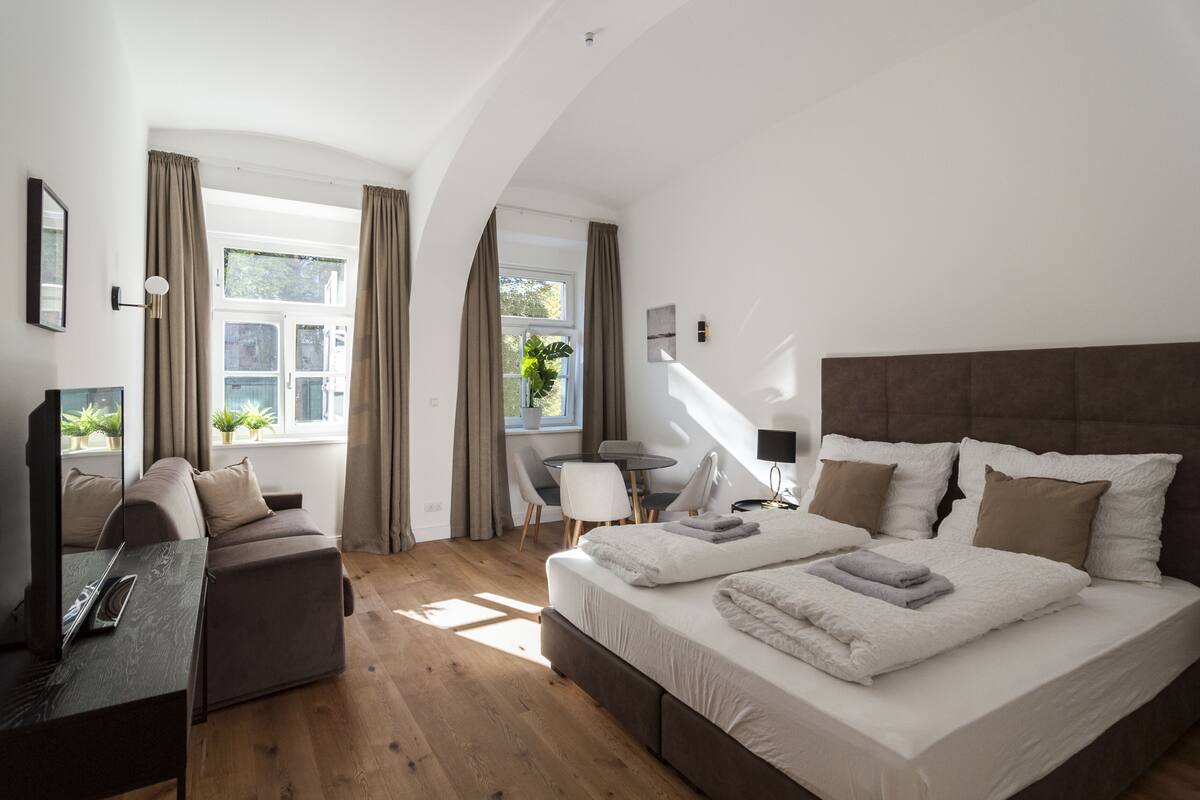 Um quarto moderno com uma cama grande, um sofá, uma escrivaninha e uma cadeira.