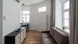 Ein modernes Wohnzimmer mit einer Couch, einem Essbereich mit Tisch und Stühlen sowie einem großen Fenster mit Vorhängen.