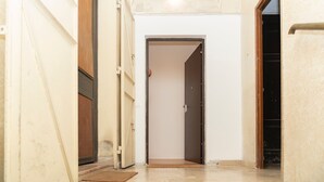 A hallway with a door leading to a room. The hallway has a tiled floor and a light fixture on the ceiling. - MASSIM'HOME HOUSE NEAR THE THEATRE (Palermo)