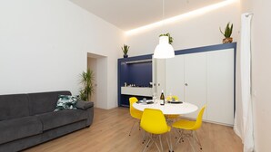 A modern living room with a grey sofa, yellow chairs, a white table, and a blue accent wall. - MASSIM'HOME HOUSE NEAR THE THEATRE (Palermo)
