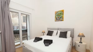 A bedroom with a bed, two bedside tables, a window with curtains, and a painting on the wall. - MASSIM'HOME HOUSE NEAR THE THEATRE (Palermo)