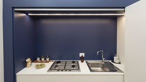 A compact kitchen with a gas stove, sink, and a blue accent wall. - MASSIM'HOME HOUSE NEAR THE THEATRE (Palermo)
