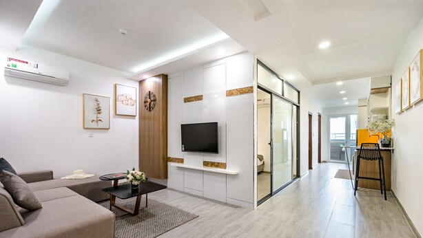 A modern living room with a sofa, coffee table, and TV. There is a hallway leading to a dining area with a chair and table. - The Sea House Nha Trang (Nha Trang)