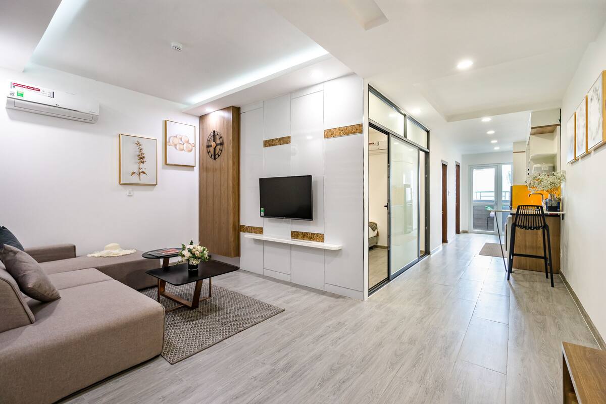 Een moderne woonkamer met een bank, een salontafel en een flatscreen televisie aan een witte muur.