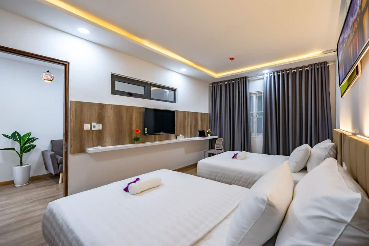 Een hotelkamer met twee bedden, een televisie, een bureau en een potplant.