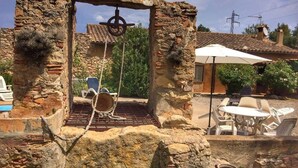 An outdoor area with stone ruins, a swing, and a patio with chairs and a table. - La Rajoleria d'Esclanyà, rural house with private swimming pool on the Costa Brava (esclanyà)
