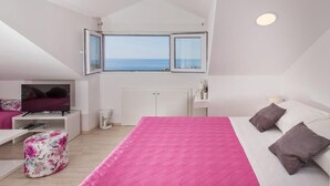 A bedroom with a large bed, a TV, a window with a view, and a white wardrobe. - Rooms on Konalu (Dubrovnik)
