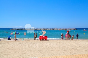 Una playa con una torre de salvavidas, sillas y sombrillas.
