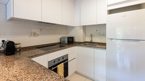 A compact kitchen with white cabinets, a built-in microwave, a stainless steel sink, and a dishwasher. - Beachfront Apartment for 4 people with Air Conditioner - UHC TXINGUDI 139 (Cambrils)