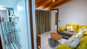 Una sala de estar moderna con un sofá, una mesa de centro y una cabina de ducha de vidrio.