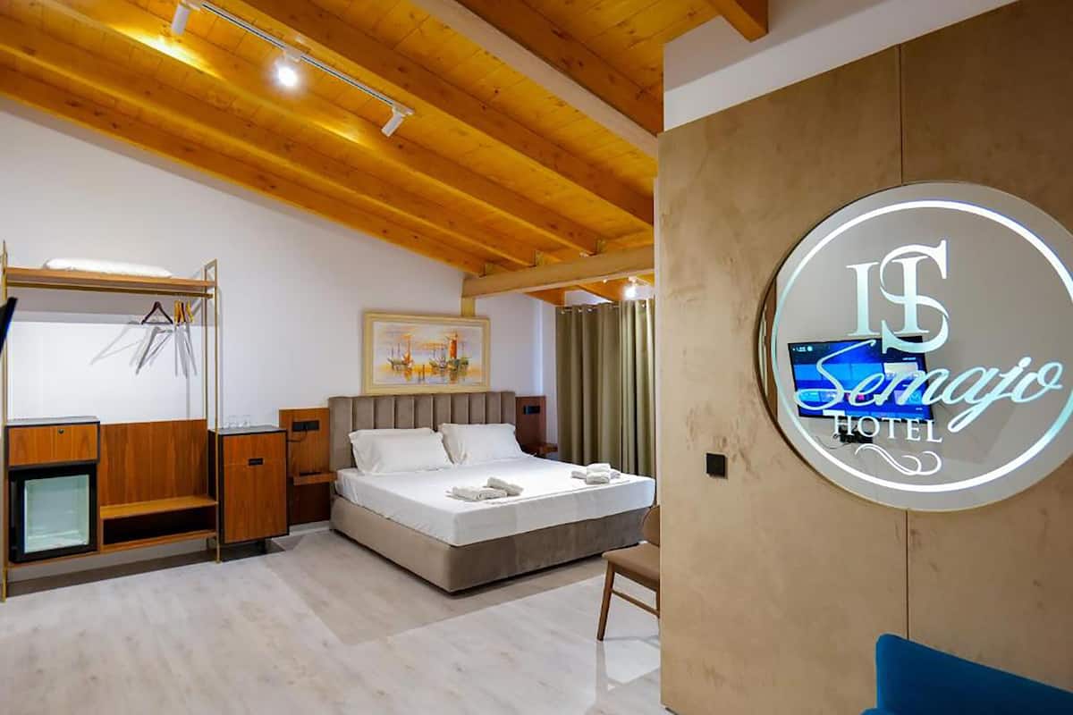 A hotel room with a bed, a desk, a chair, and a TV.