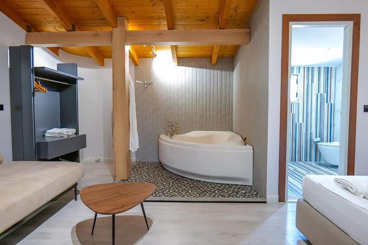 A modern bathroom with a freestanding bathtub, a wooden ceiling, and a view of a balcony.
