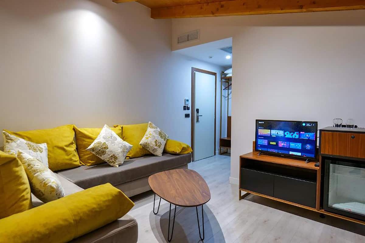 A modern living room with a sofa, a coffee table, and a television on a wooden stand.