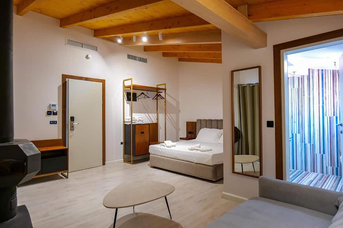 A modern bedroom with a bed, a small table, a wardrobe, and a mirror.