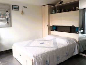 Une chambre à coucher avec un lit, une armoire, une table de chevet et un mur orné d’un tableau.