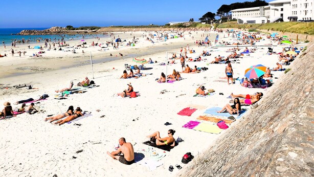 En fullsatt strand där folk solar och badar.