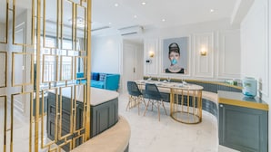Ein moderner Essbereich mit Marmorboden, einem runden Tisch mit goldenen Akzenten und blauen Sitzmöbeln.