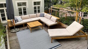 Un espace extérieur aménagé, abrité et doté d’un canapé, d’un fauteuil et d’une table basse.