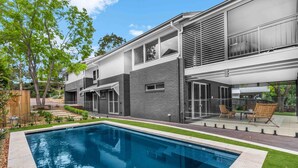 A modern two-story house with a swimming pool, a patio with outdoor furniture, and a well-maintained garden. - Hunter Treehouse - Gorgeous golf course getaway, at The Vintage Resort (Rothbury)