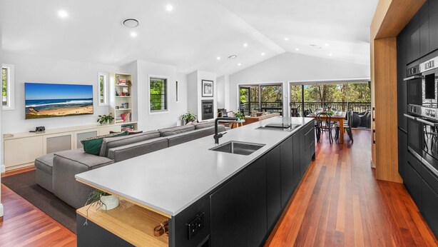 A modern kitchen with a large island, black cabinetry, and a dining area with a view of the outdoors. - Hunter Treehouse - Gorgeous golf course getaway, at The Vintage Resort (Rothbury)