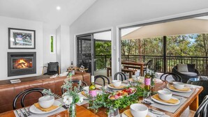 A dining area with a fireplace, a large window, and a view of trees. - Hunter Treehouse - Gorgeous golf course getaway, at The Vintage Resort (Rothbury)