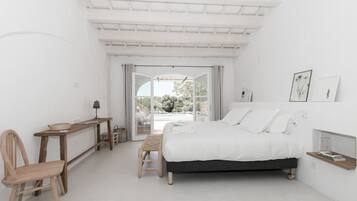A minimalist bedroom with a bed, a desk, and a chair.