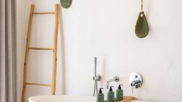 Une salle de bain avec une baignoire sur pieds, une échelle en bois et deux plantes fixées au mur.