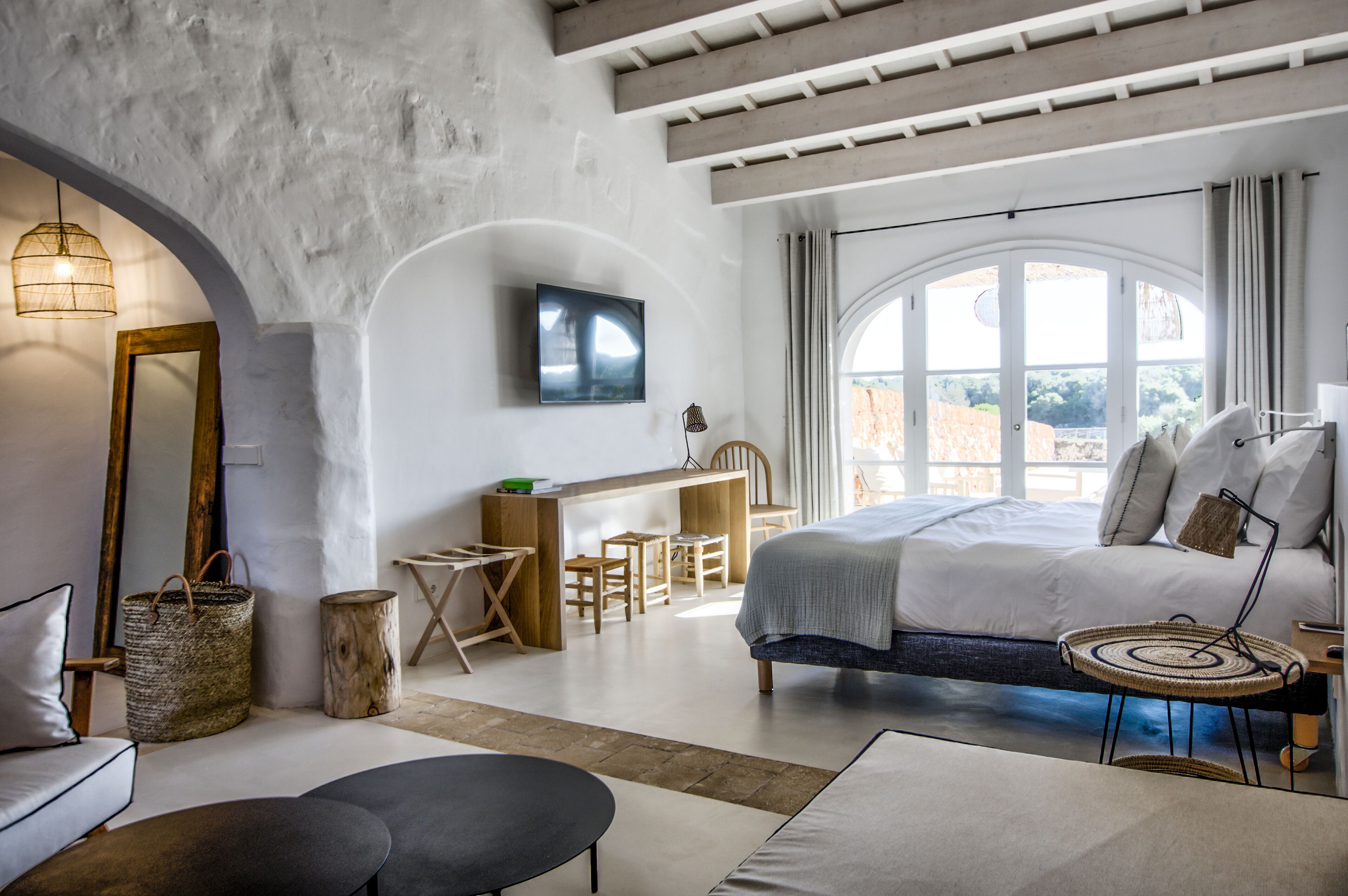 A modern bedroom with a large bed, a desk, and a TV.