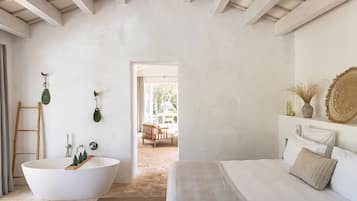 Un dormitorio con una cama grande, una bañera blanca y una escalera de madera.