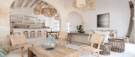 A spacious room with a wooden table, wicker chairs, and a large hanging light fixture.