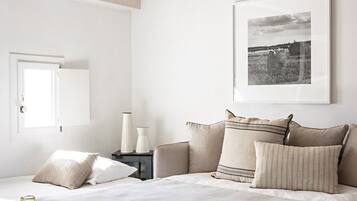 A bedroom with a large bed, a ceiling fan, a framed picture, bedside tables, and a window.