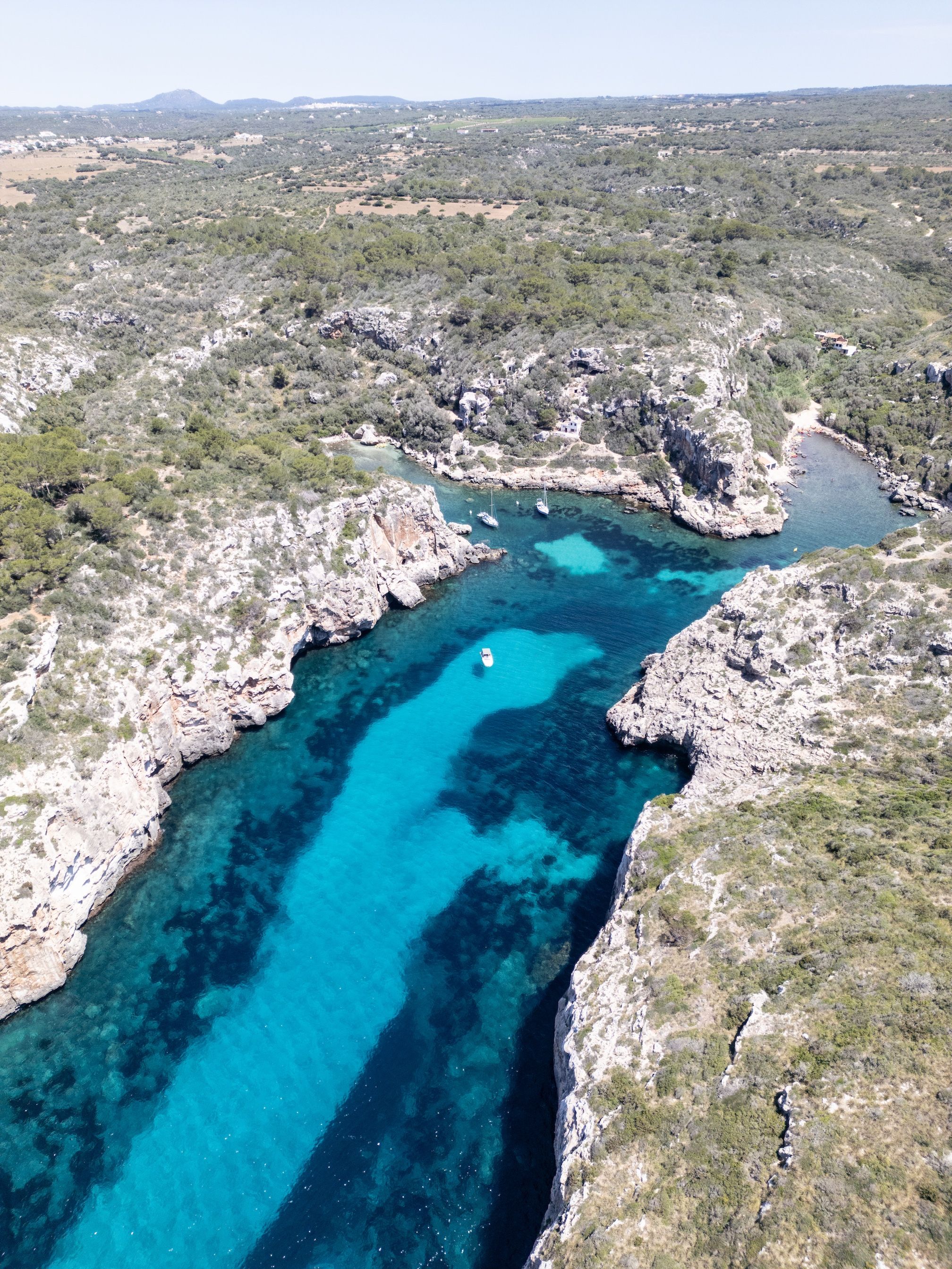 Un paisaje costero con aguas azul cristalino, terreno rocoso y vegetación escasa.