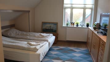 Un dormitorio con dos camas, una ventana con persianas, un radiador, un aparador y un cuadro en la pared.