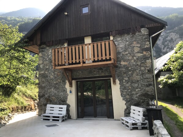 Un edificio rústico con balcón de madera, paredes de piedra y vista a las montañas.
