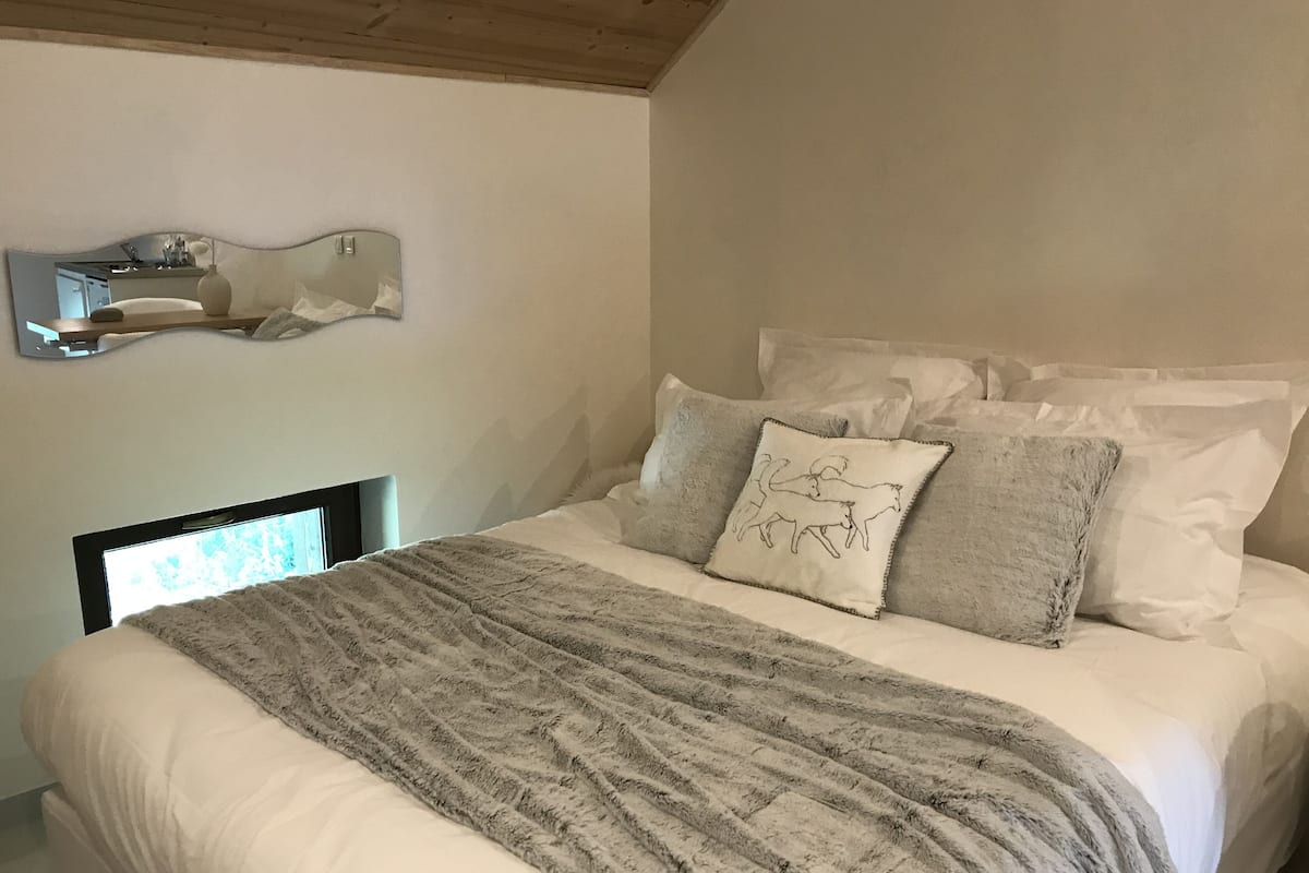 Une chambre à coucher avec un grand lit, une tête de lit, un miroir et une étagère fixée au mur.
