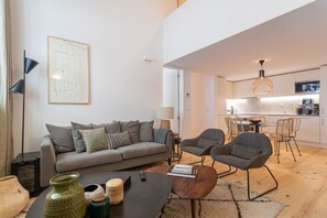 Ein modernes Wohnzimmer mit grauem Sofa, einem Couchtisch und einem Essbereich mit Stühlen.