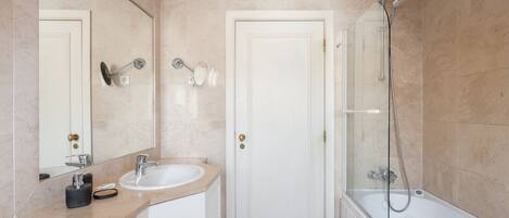 A modern bathroom with a sink, mirror, and shower.