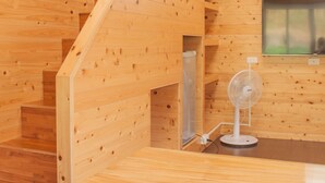 A wooden interior with a staircase, a fan, and a window.