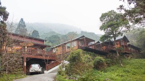 A rustic lodge with a dirt road leading to a car parked at a tunnel entrance.