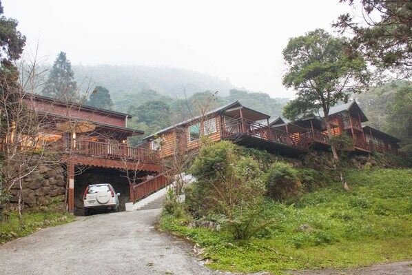 A rustic lodge with a dirt road leading to a car parked at a tunnel entrance. - Xitou Star (Lugu)