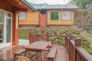 A wooden deck with picnic tables and a covered seating area, overlooking a traditional log cabin with large windows and a wooden railing. - Xitou Star (Lugu)