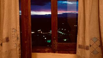 Une pièce offrant une vue sur le paysage urbain au crépuscule, à travers une fenêtre ouverte.